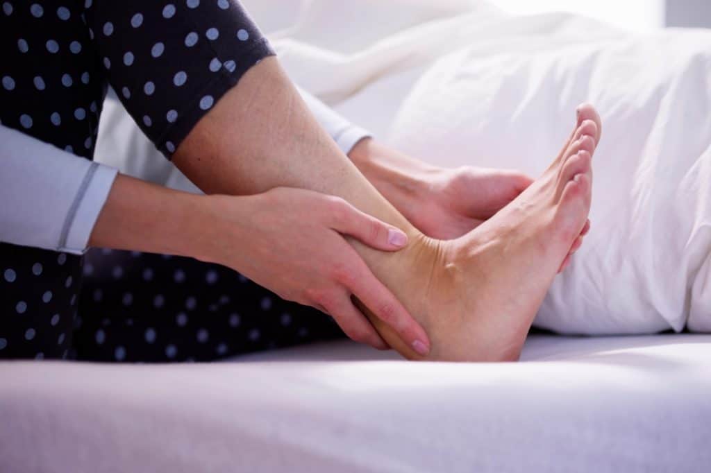 A woman suffers from foot and ankle pain as she wakes from a sleep