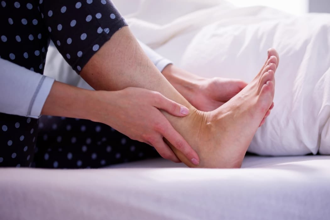 A woman suffers from foot and ankle pain as she wakes from a sleep